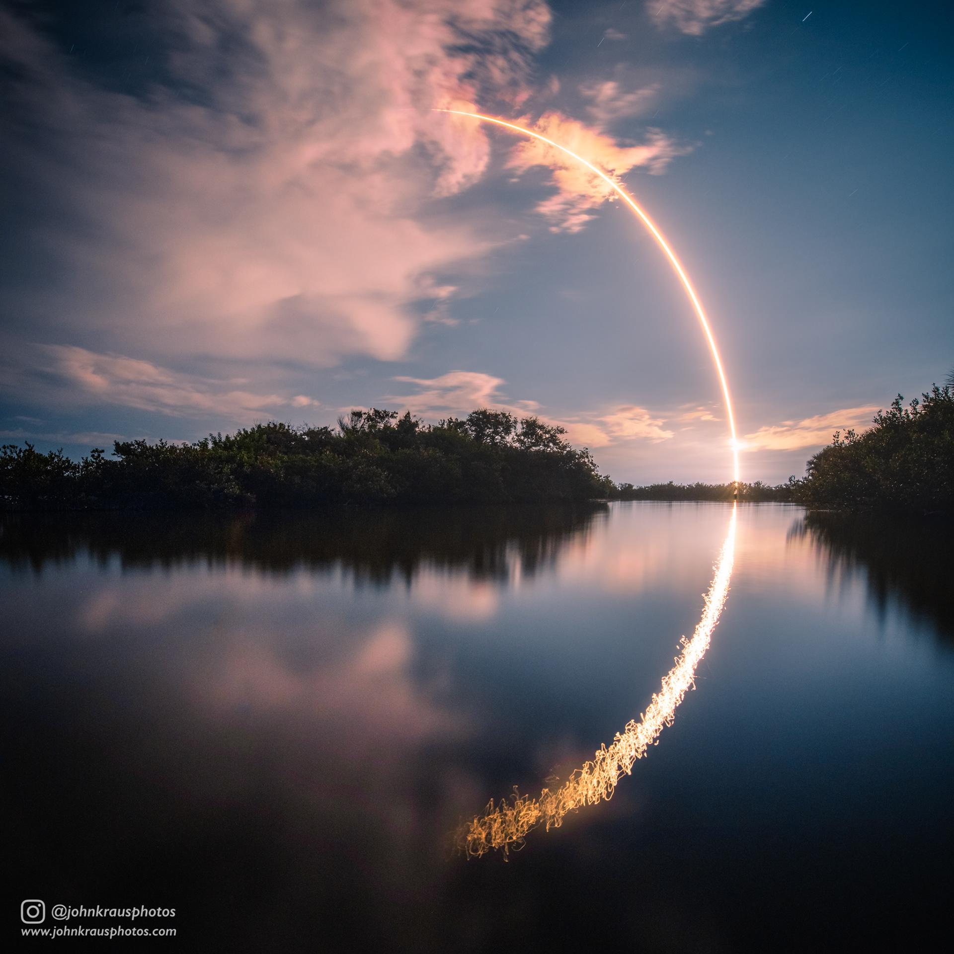 Rocket launching above a lit horizon with reflected light on water